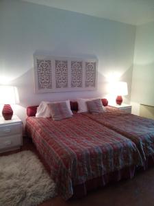 a bedroom with a bed with a red blanket and two lamps at Cozy summer house in Alvor