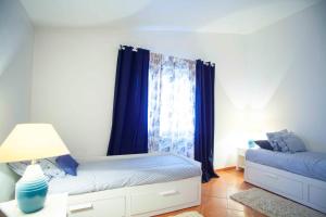 a bedroom with a bed and a window with blue curtains at Cozy summer house in Alvor