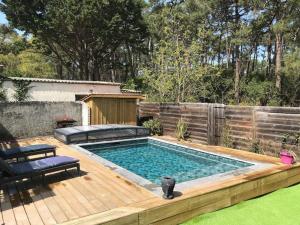 a swimming pool in a backyard with a wooden deck at Villa Welcome in Lacanau-Océan