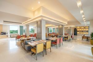 a dining room with tables and chairs and windows at Vivanta Ahmedabad SG Highway in Ahmedabad