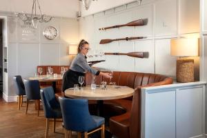 a woman is serving wine glasses in a restaurant at The Victoria Hotel in Bamburgh