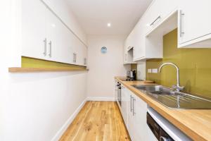 a kitchen with white cabinets and a sink at 2 bedroom apartment on Peebles High Street in Peebles