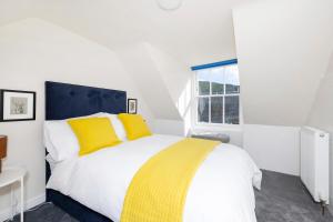 a bedroom with a bed with yellow pillows and a window at 2 bedroom apartment on Peebles High Street in Peebles