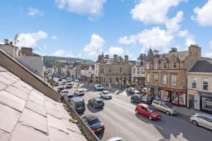 una concurrida calle de la ciudad con coches aparcados en la carretera en 2 bedroom apartment on Peebles High Street, en Peebles