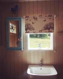 a bathroom with a sink and a window with animals on the wall at Thistlebank Yurt in Llangollen