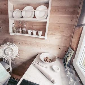 a small kitchen with a table and plates on a shelf at Morska Fala Domki in Pobierowo +35 photos