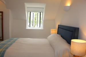 a bedroom with a bed with two lamps and a window at Coot Cottage in Somerford Keynes