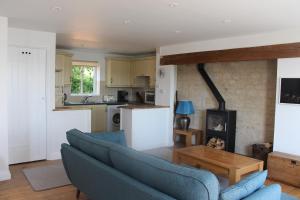 a living room with a couch and a kitchen at Coot Cottage in Somerford Keynes