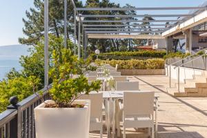 una fila de mesas y sillas blancas en un balcón en Gran Talaso Hotel Sanxenxo, en Sanxenxo