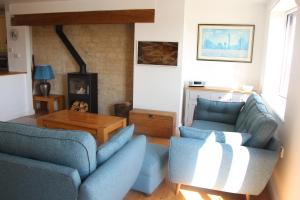 a living room with two blue chairs and a table at Coot Cottage in Somerford Keynes