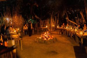 eine Gruppe von Personen, die an Tischen rund um eine Feuerstelle sitzen in der Unterkunft Hakunamatata Lodge & Health Spa/ Wedding & Conference venue in Muldersdrift