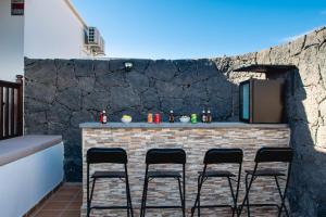 un patio avec un bar avec quatre tabourets dans l'établissement Villa Vista Reina - Luxury 6 Bedroom - Heated Pool- Views - Pool Table - Vista Lobos - Playa Blanca, à Playa Blanca