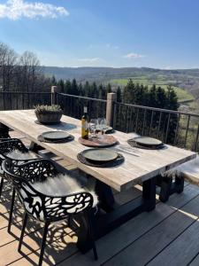 a wooden table sitting on a deck with chairs and a tableablish at Suites de la vallée 6 in Érezée