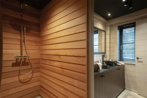 a bathroom with wooden walls and a shower stall at Suites de la vallée 6 in Érezée