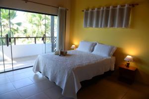 a bedroom with a white bed and a large window at Pousada Vila Bacana in São Miguel do Gostoso
