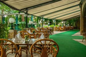 a restaurant with wooden tables and chairs on a green floor at Ensana Grand Margaret Island in Budapest +60 photos