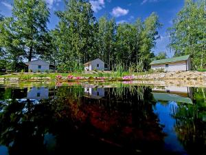 um reflexo de casas na água com flores rosas em Obora resort em Lanskroun
