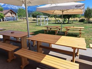 a group of wooden picnic tables with an umbrella at GLAMPING HOUSE RANČ LUŽE in Luže