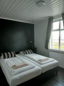 two twin beds in a bedroom with a window at Gistihús Hólmavíkur in Hólmavík