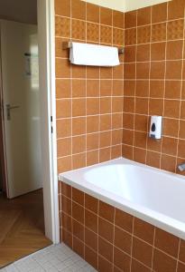 y baño con bañera y azulejos de color naranja. en Autobahn Hotel Pfungstadt Ost, en Pfungstadt