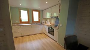 een keuken met witte kasten en een houten vloer bij Les Chalets du Parc aux Etoiles - Cimes et Neige in Puy-Saint-Vincent