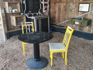 a table with two yellow chairs and a stove at Lavendelmond Glamping in Barntrup