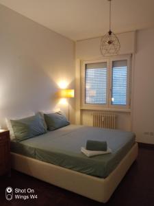 a bedroom with a bed with a green blanket and two windows at Appartamento DeLuxe con parcheggio gratuito in Segrate