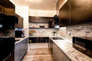 a kitchen with black cabinets and marble counter tops at Apartmán Sabína in Liptovský Mikuláš