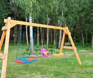 a wooden swing set with two chairs in the grass at Letniskowy domek z Bali in Myszyniec