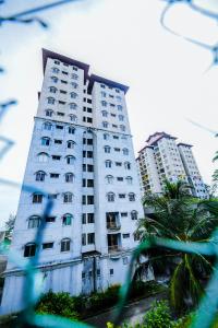 een hoog wit gebouw met palmbomen ervoor bij OYO Home 90466 JC Sunshine Bay Resort Apartment Port Dickson in Port Dickson