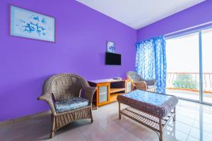 een woonkamer met paarse muren en een tafel en stoelen bij OYO Home 90466 JC Sunshine Bay Resort Apartment Port Dickson in Port Dickson
