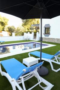 una piscina con due sedie a sdraio e un ombrellone di Casa La Herradura 2 a Vejer de la Frontera