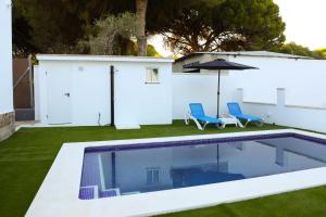 a swimming pool with two blue chairs and an umbrella at Casa La Herradura 2 in Vejer de la Frontera