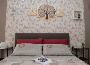 a bed with two pillows and a tree on a wall at IL CORTILETTO - Verduno in Verduno