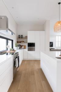 uma cozinha branca com armários brancos e piso de madeira em Sunset Villa - brand new home 200m from the beach em Plettenberg Bay