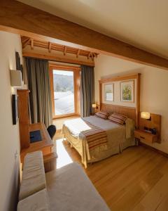 a bedroom with two beds and a large window at Hotel y Cabañas Le Village in San Martín de los Andes