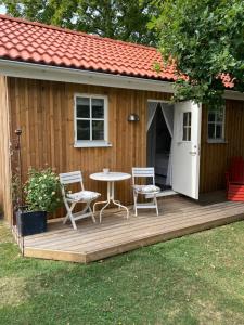 a wooden deck with a table and chairs and a house at Ekverandan in Höganäs