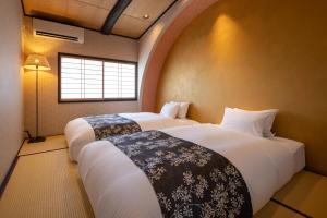two beds in a room with a window at 京恋 黄金屋 in Kyoto