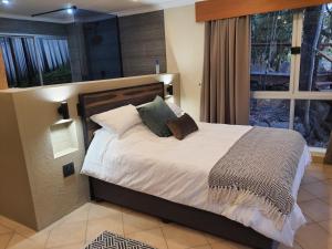 a bedroom with a large bed with white sheets and pillows at Bikkurim Inn in Nelspruit