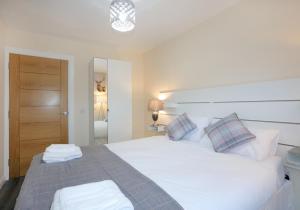 1 dormitorio con 1 cama blanca grande y 2 almohadas en Canal View Cottage, 