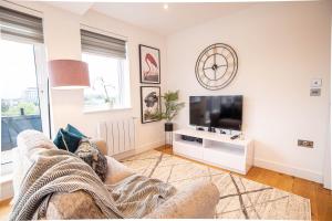 uma sala de estar com um sofá e uma televisão em Deluxe & Chic 1 & 2 Bed Apts near Heathrow, Legoland, & Windsor Slough em Slough