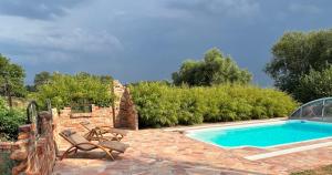 ein Swimmingpool mit zwei Stühlen neben einer Steinterrasse in der Unterkunft Raminorca Ferienwohnung mit großem Pool -mobiles Frühstückspaket kann man bei uns dazu buchen in Ramin