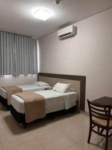 1 dormitorio con 2 camas, mesa y silla en Hotel Cadori, en Paiçandu