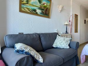 - un canapé bleu dans le salon avec des oreillers dans l'établissement Studios für 2 Personen am Strand, à Arguineguín
