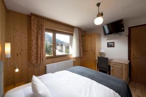 Schlafzimmer mit einem Bett, einem Schreibtisch und einem Fenster in der Unterkunft Hotel le Beausite in Saint-Luc