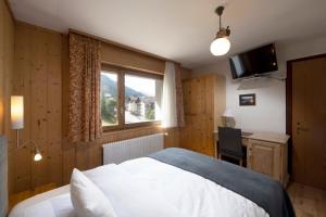 a bedroom with a bed and a desk and a window at Hotel le Beausite in Saint-Luc