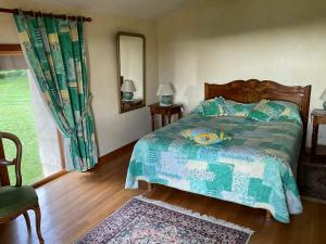 1 dormitorio con 1 cama con edredón verde en A l oree du bois, en Futeau