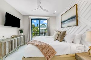 a white bedroom with a bed and a balcony at Endless Summer in Sarasota
