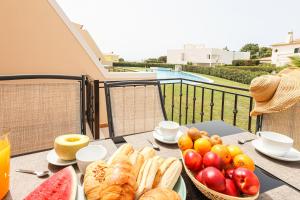 una mesa con una bandeja de pan y fruta en el balcón en House J São Rafael - By Bedzy en Albufeira