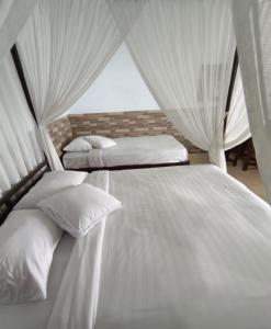 two beds in a room with white curtains at Puri Sunset Homestay in Munduk